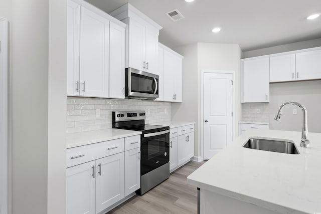 623 Blackthorne Cir NW, Calabash, NC 28467 - kitchen featuring appliances with stainless steel finishes, light wood-style flooring, recessed lighting, decorative backsplash, and white cabinetry