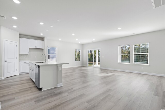 kitchen with stainless steel dishwasher, sink, an island with sink, and a wealth of natural light