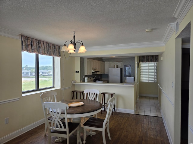 dining room with a textured ceiling, a notable chandelier, dark hardwood / wood-style floors, and crown molding