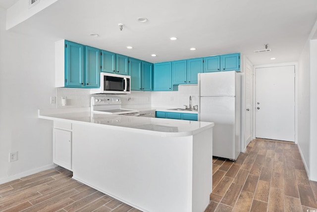 kitchen featuring hardwood / wood-style flooring, kitchen peninsula, and white appliances