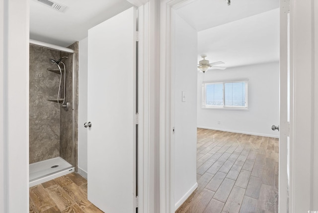 bathroom with ceiling fan, hardwood / wood-style flooring, and tiled shower