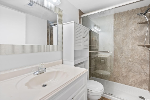 bathroom featuring vanity, a shower with shower door, and toilet