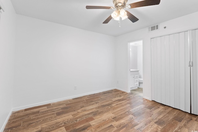 unfurnished bedroom featuring a closet, ensuite bath, ceiling fan, and hardwood / wood-style flooring