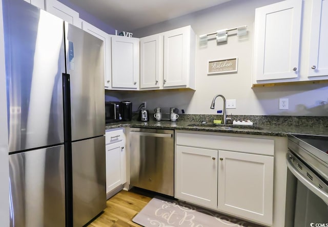 kitchen with dark stone countertops, sink, stainless steel appliances, and white cabinets