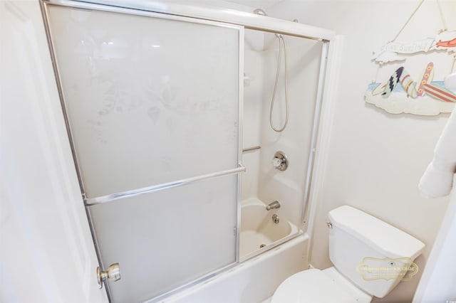 bathroom featuring bath / shower combo with glass door and toilet