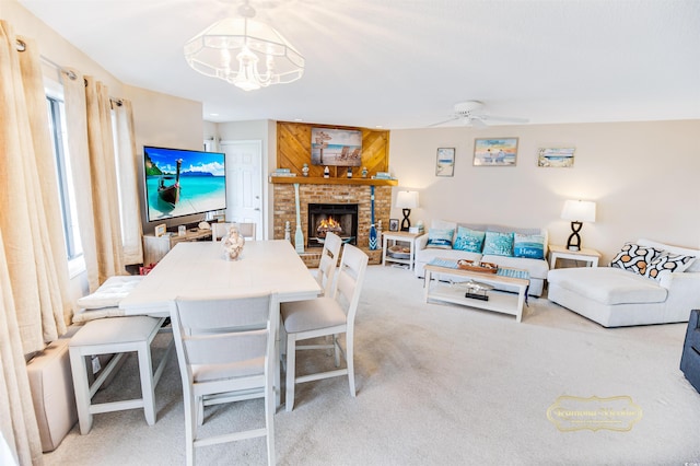 carpeted living room with ceiling fan with notable chandelier and a fireplace