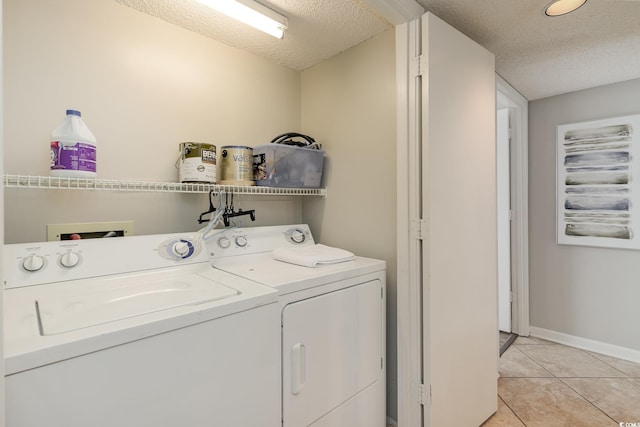 laundry room with a textured ceiling, separate washer and dryer, and light tile patterned floors