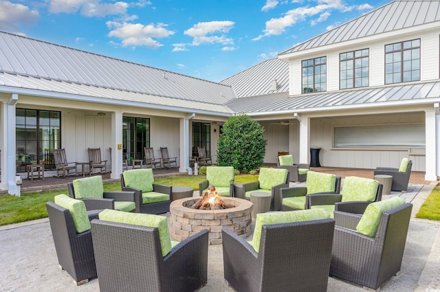 view of patio with a garage and an outdoor living space with a fire pit