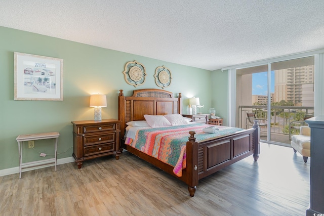 bedroom featuring light hardwood / wood-style flooring, a textured ceiling, and access to exterior