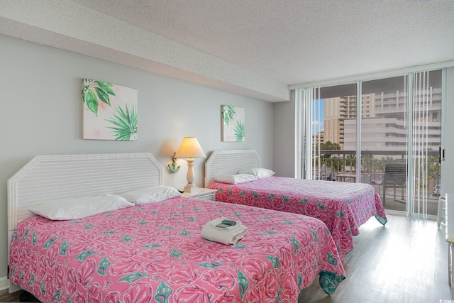 bedroom featuring hardwood / wood-style floors, a textured ceiling, a wall of windows, and access to outside