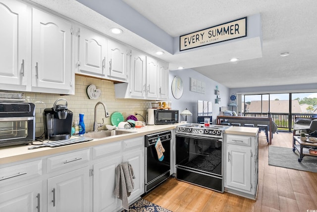 kitchen with light hardwood / wood-style floors, sink, white cabinets, kitchen peninsula, and black appliances