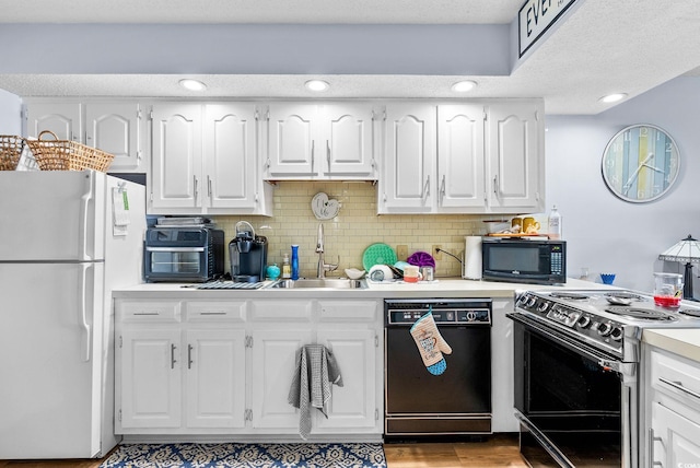 kitchen with tasteful backsplash, white cabinets, black appliances, light hardwood / wood-style flooring, and sink