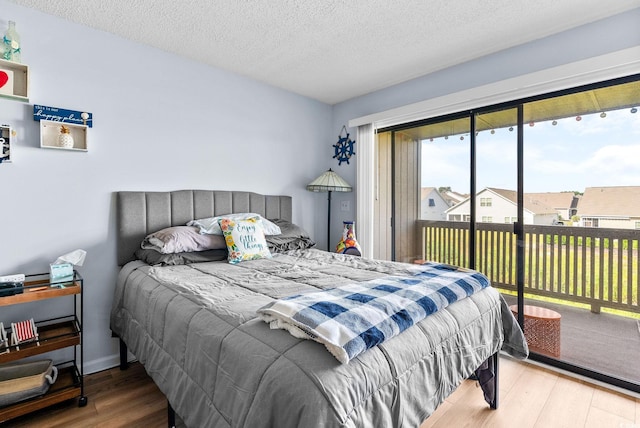 bedroom featuring a textured ceiling, hardwood / wood-style floors, and access to exterior