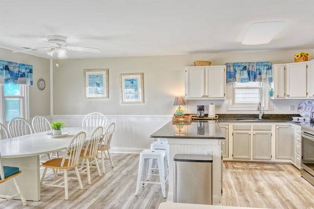 kitchen with light wood-type flooring, white cabinetry, sink, and ceiling fan