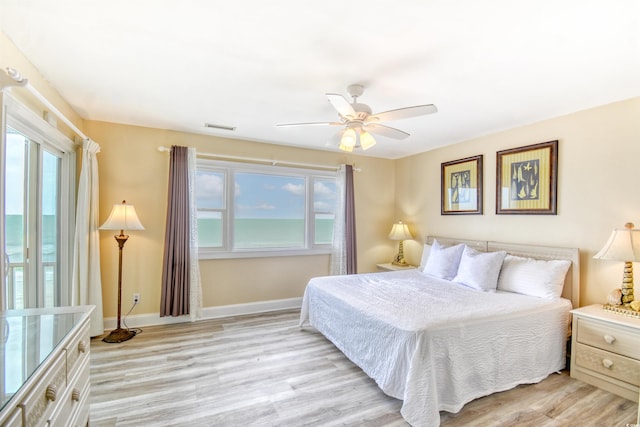 bedroom featuring ceiling fan, light wood-type flooring, and multiple windows