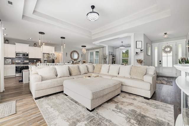 living room featuring light hardwood / wood-style flooring and a raised ceiling