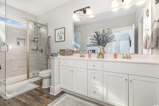 bathroom with vanity, a shower with shower door, toilet, and hardwood / wood-style flooring