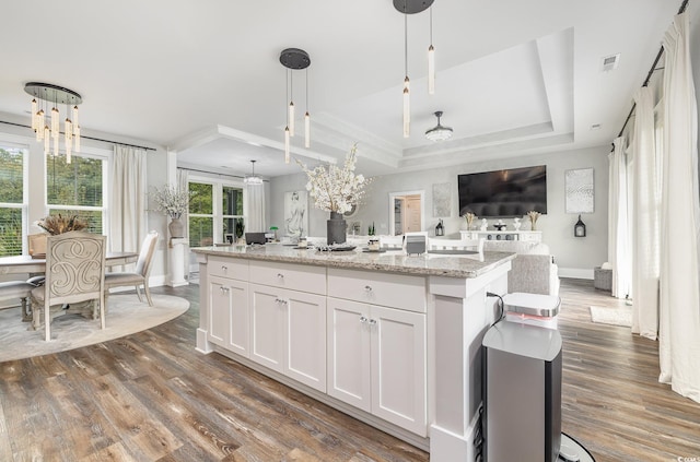 kitchen featuring white cabinets, plenty of natural light, a center island with sink, and hanging light fixtures