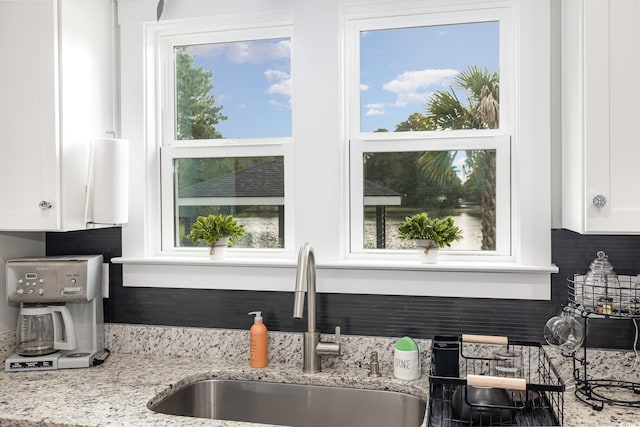 kitchen with white cabinetry, sink, and light stone counters