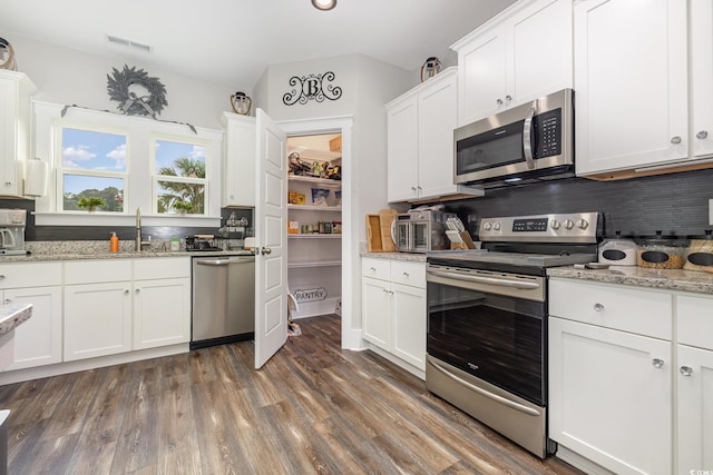 kitchen with white cabinets, light stone countertops, stainless steel appliances, dark hardwood / wood-style floors, and sink