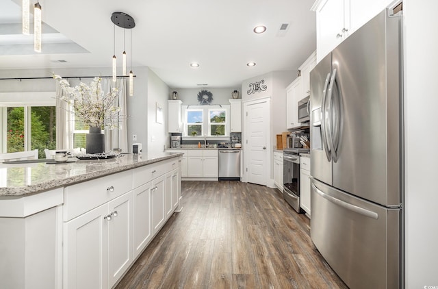 kitchen featuring pendant lighting, white cabinets, appliances with stainless steel finishes, dark hardwood / wood-style flooring, and light stone countertops