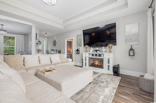 living room with a tray ceiling and dark hardwood / wood-style flooring