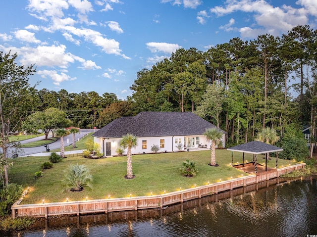 back of house with a water view and a yard