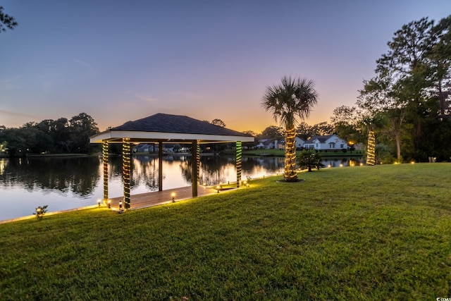 dock area with a lawn and a water view