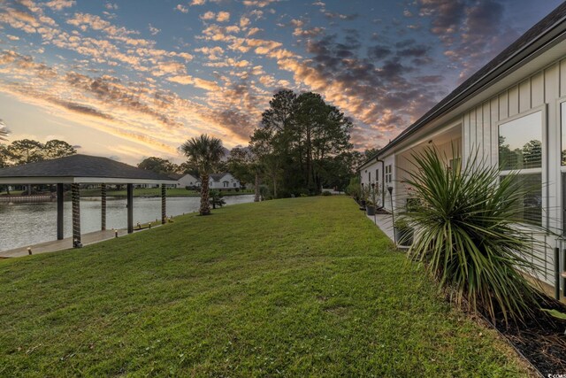 yard at dusk featuring a water view