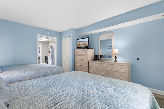 bedroom with stainless steel refrigerator and dark hardwood / wood-style floors