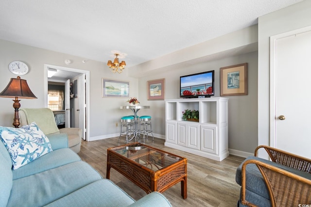 living room featuring a textured ceiling, light wood-type flooring, and a chandelier