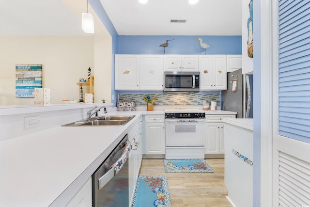 kitchen featuring appliances with stainless steel finishes, light hardwood / wood-style floors, white cabinetry, decorative light fixtures, and sink