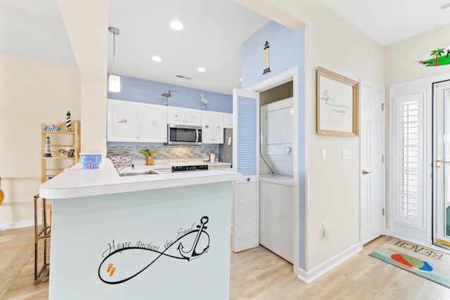 kitchen featuring kitchen peninsula, stacked washer and clothes dryer, a kitchen bar, white cabinetry, and light hardwood / wood-style floors