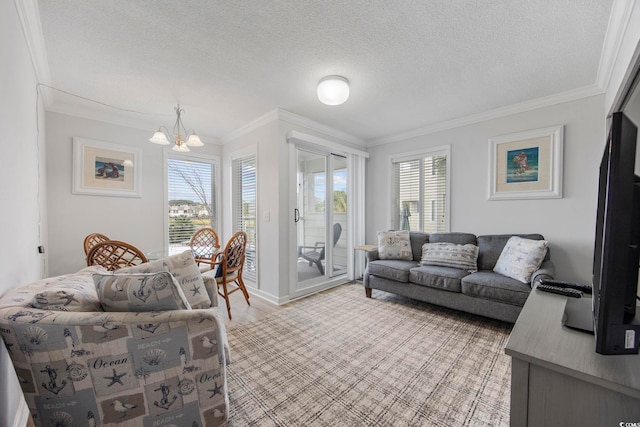 living area featuring a textured ceiling, ornamental molding, a wealth of natural light, and an inviting chandelier