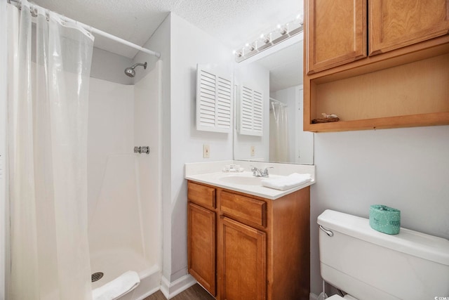 bathroom featuring toilet, a shower stall, a textured ceiling, and vanity