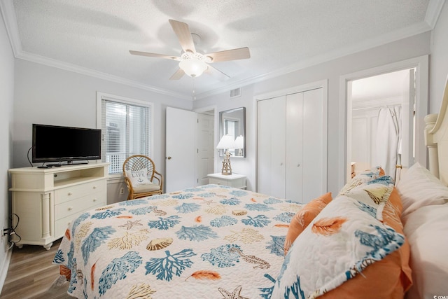 bedroom featuring crown molding, a closet, visible vents, a textured ceiling, and wood finished floors