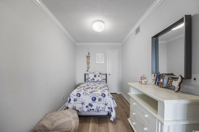 bedroom with dark wood-style floors, visible vents, ornamental molding, a textured ceiling, and baseboards