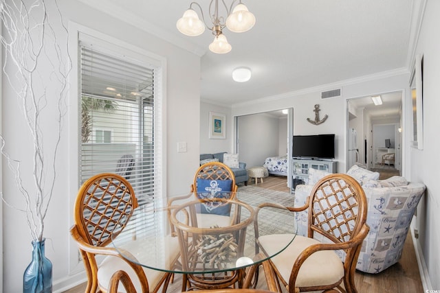 dining area featuring visible vents, crown molding, a notable chandelier, and wood finished floors