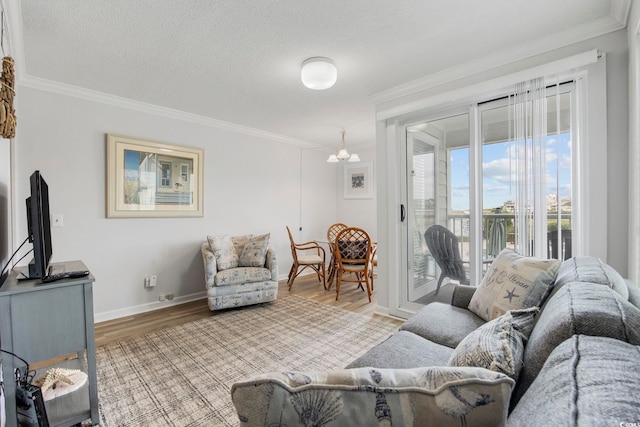 living area with light wood finished floors, a textured ceiling, baseboards, and crown molding