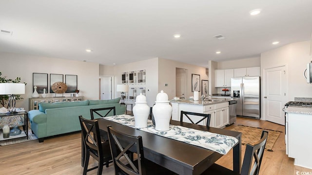 dining space featuring light wood-type flooring and sink