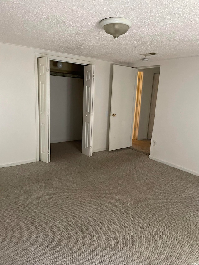 unfurnished bedroom with a textured ceiling, a closet, and carpet floors