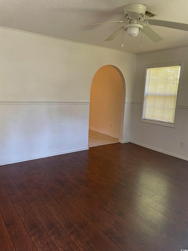 empty room with a textured ceiling, dark hardwood / wood-style floors, and ceiling fan