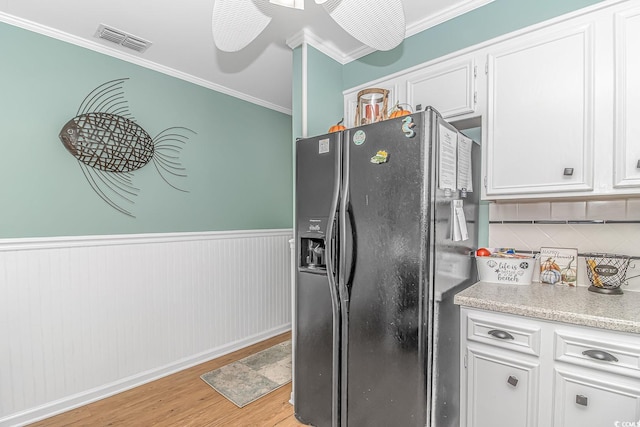 kitchen with tasteful backsplash, light wood-type flooring, black refrigerator with ice dispenser, white cabinets, and ornamental molding