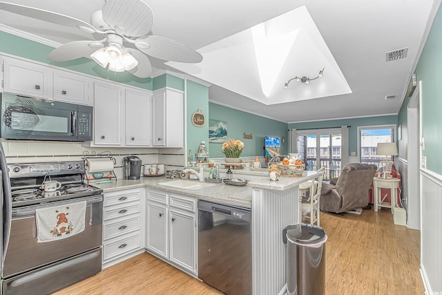 kitchen featuring kitchen peninsula, white cabinets, black appliances, light hardwood / wood-style floors, and sink