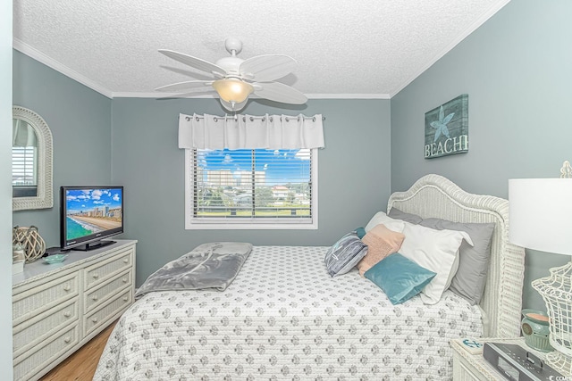 bedroom with ceiling fan, hardwood / wood-style flooring, ornamental molding, and a textured ceiling