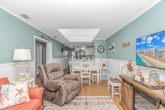 living room featuring ornamental molding, a skylight, light hardwood / wood-style flooring, and ceiling fan