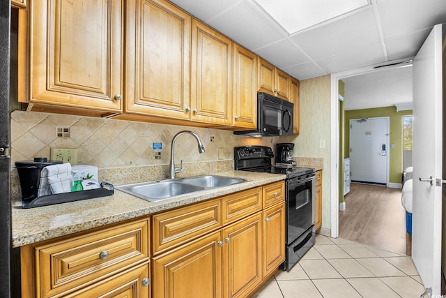 kitchen featuring tasteful backsplash, black appliances, sink, a paneled ceiling, and light tile patterned floors