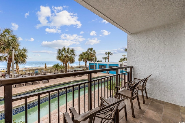 balcony featuring a water view and a view of the beach