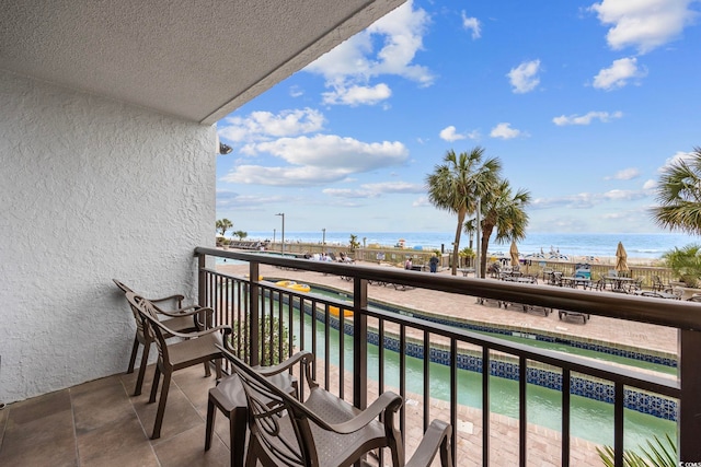 balcony featuring a water view and a beach view