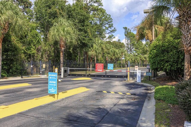9772 Leyland Dr Unit 9772-9, Myrtle Beach, SC 29572 - view of asphalt road with a gate, curbs, a gated entry, and view of wooded area